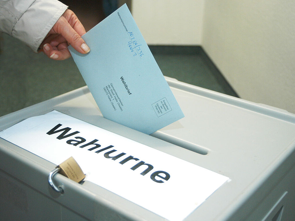 Eine Hand wirft einen Stimmzettel in eine Wahlurne